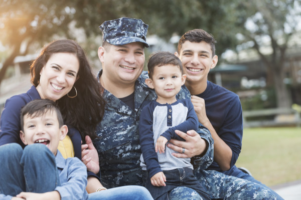 A military family sitting together outside smiling