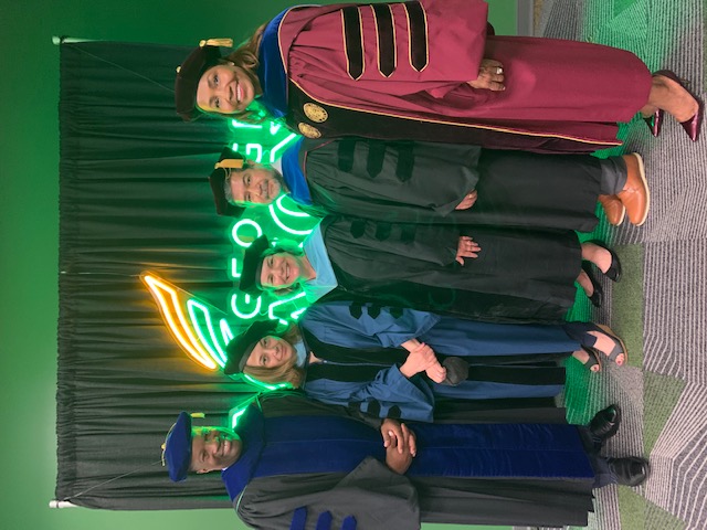 Five Education Leadership Program faculty members standing together in graduation robes