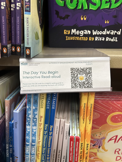 A note with a QR code hanging from a shelf with children's books