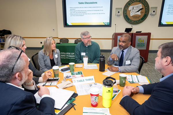 Photo of people meeting around a table in a GMU conference room